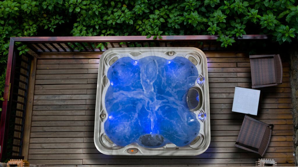 Indoor swim spa with a white exterior and blue interior, surrounded by tiled walls and illuminated by moonlights