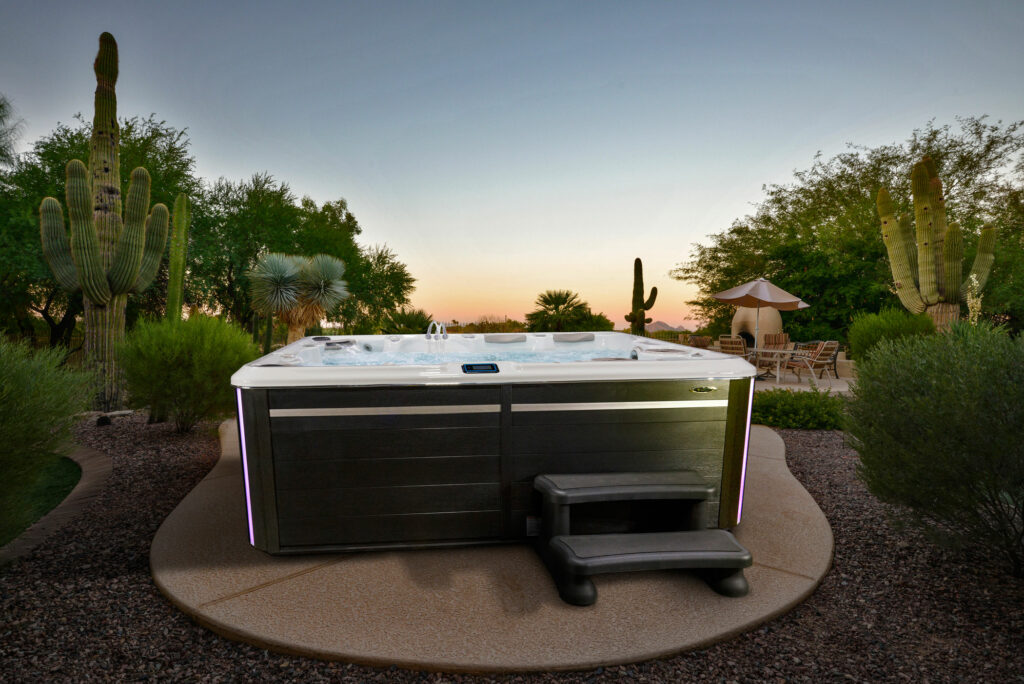 View of a swim spa installation at dusk, located on a patio surrounded by greenery