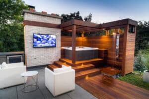 Hot tub with LED lighting on a wooden deck outdoors next to big screen TV
